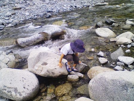 川が緩やかに伏流しているところ。大きな石に腰かけるKen