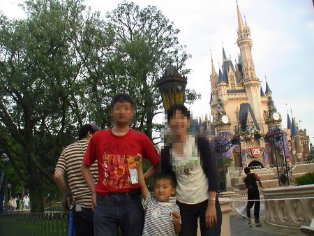 シンデレラ城をバッグに3人の記念写真。Kenは右手を上げてポーズ